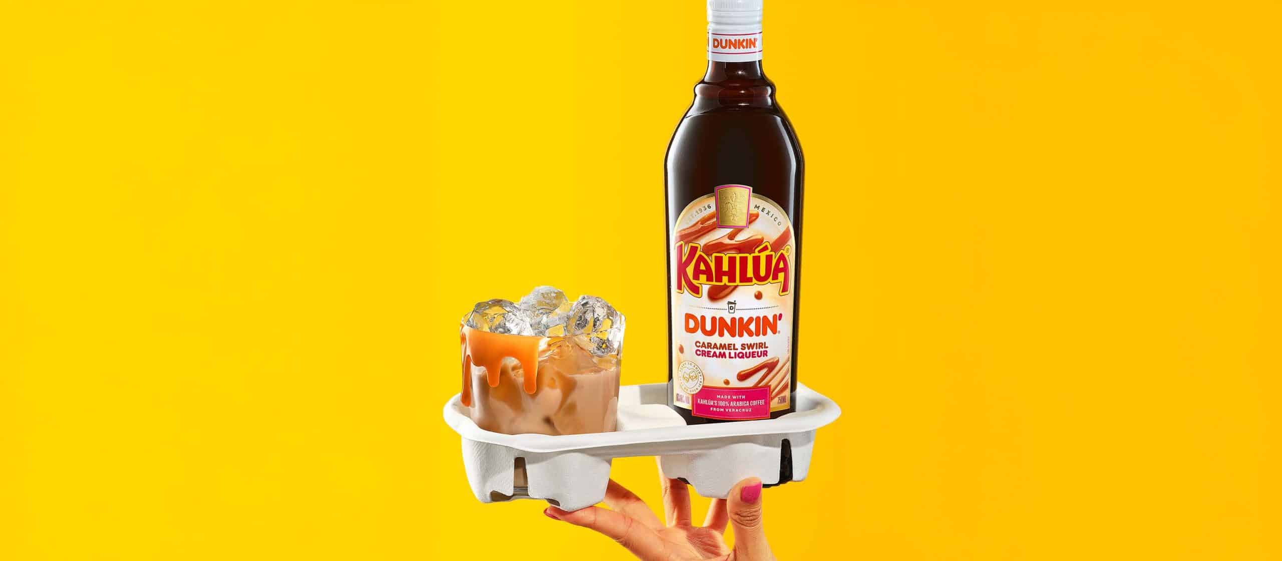 Kahlua dunkin bottle in a coffee cup holder next to a cocktail