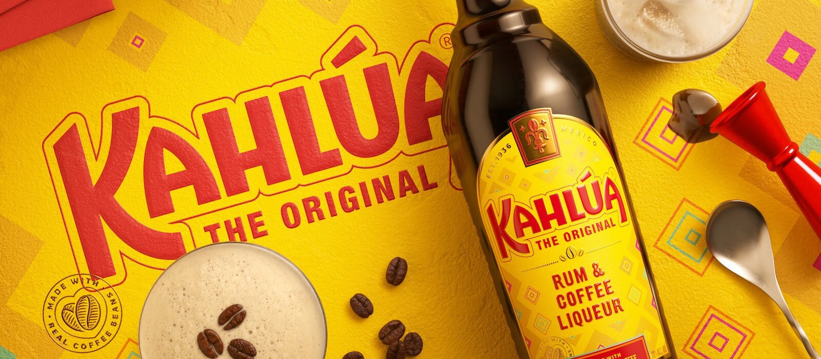 Kahlua Bottle laying on a kahlua themed background with an espresso martini